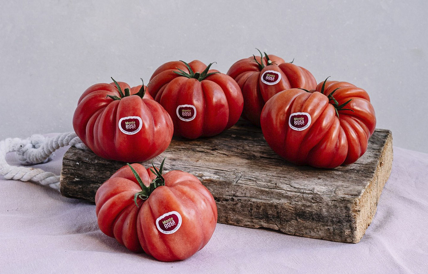 Imagen de una balda de madera con cinco tomates Monterosa posados sobre ella imagen con aire rústico, Tomates grandes y sabrosos.