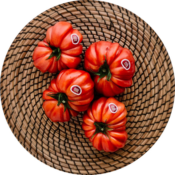 En la imagen 4 tomates Monterosa sobre un plato de madera. Imagen con vista desde arriba.
