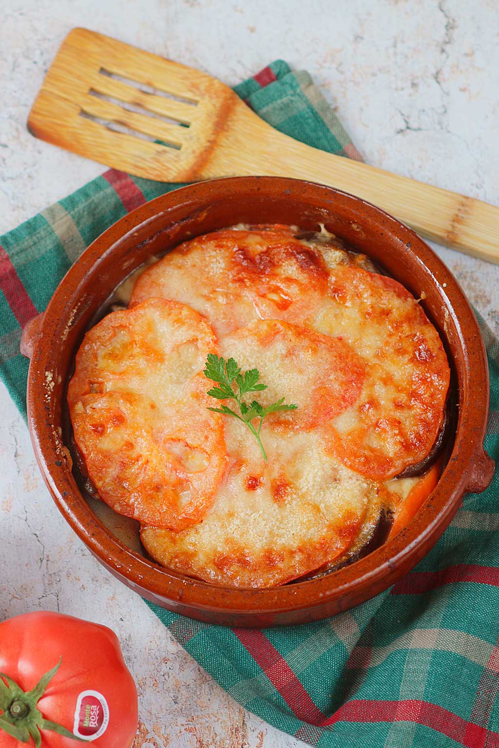 Receta de parmigiana con tomate Monterosa. Presentado en una cazuela de barro con una rasera de madera para servirlo. By Marina Ribas.